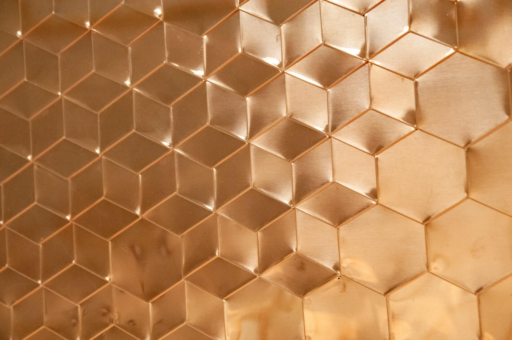 Close-up of a copper surface with a geometric, hexagonal pattern.