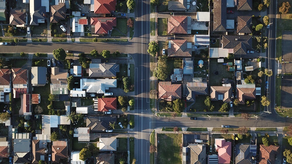 Overhead shot of a suburban area highlighting rooftops and chimney caps.