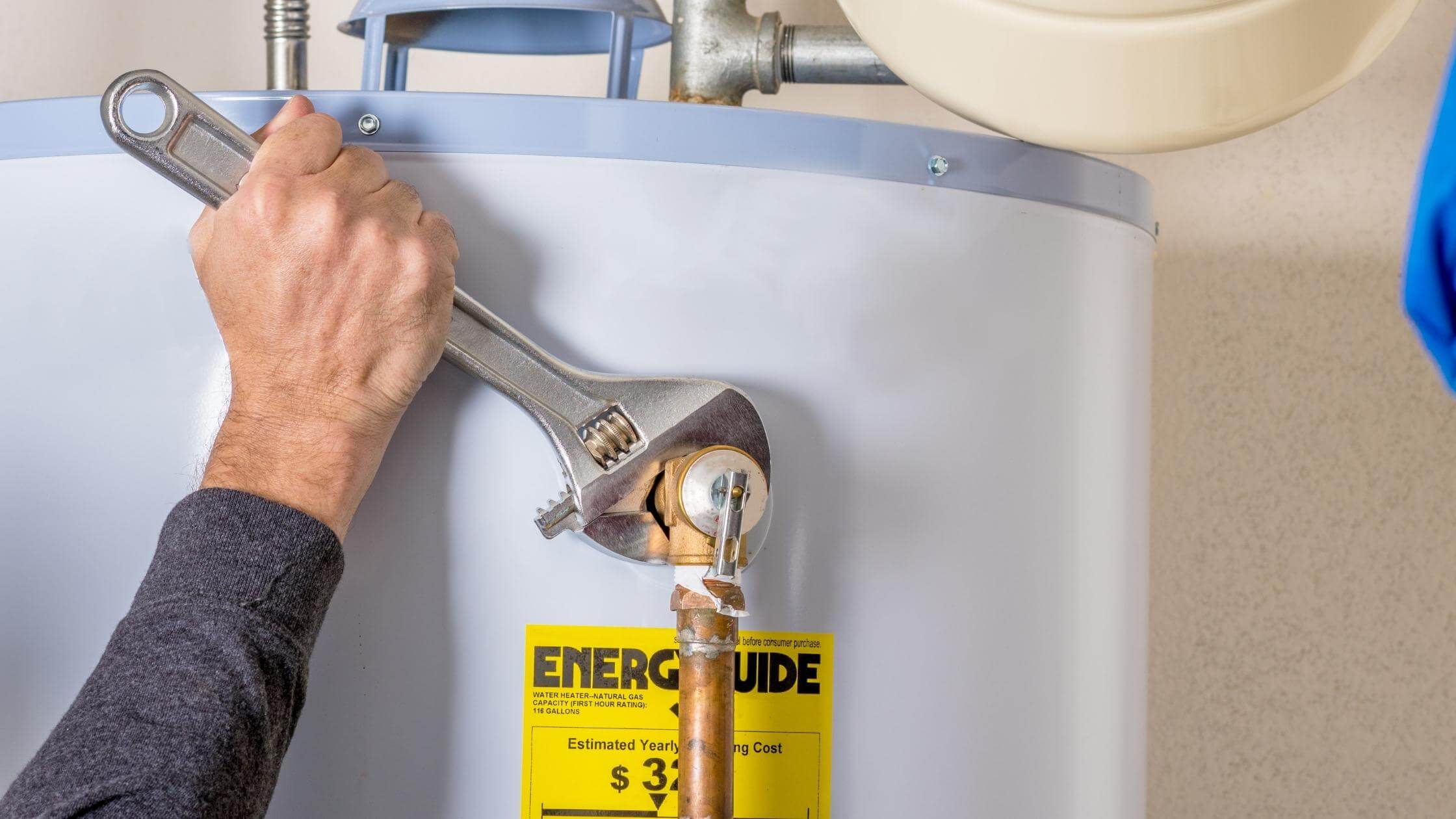 man working wrench on water heater